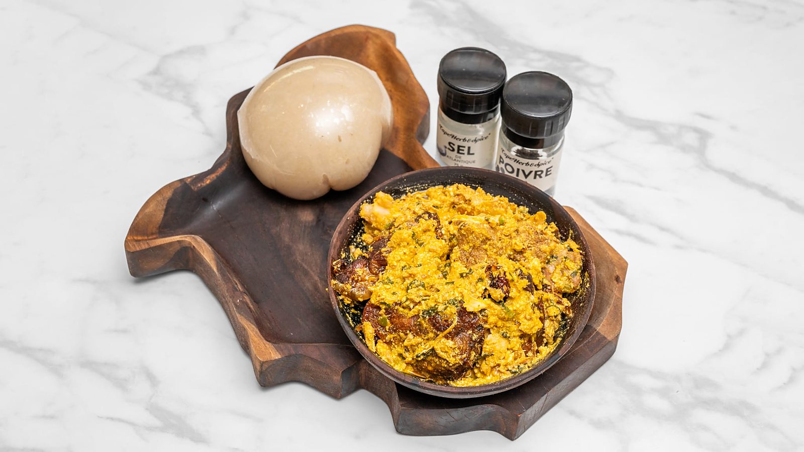 Egusi aux graines de courge et fufu sur planche en forme d'Afrique